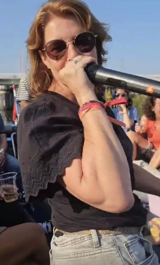 Aimée van Wijk met een microfoon, in de zon op een boot